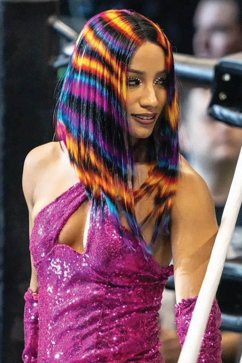 woman in pink outfit wearing yellow orange pink blue and black striped wig