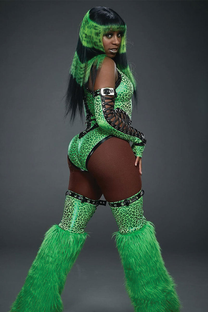 Person wearing a green costume with fur details and a green and black painted wig. the background is grey.