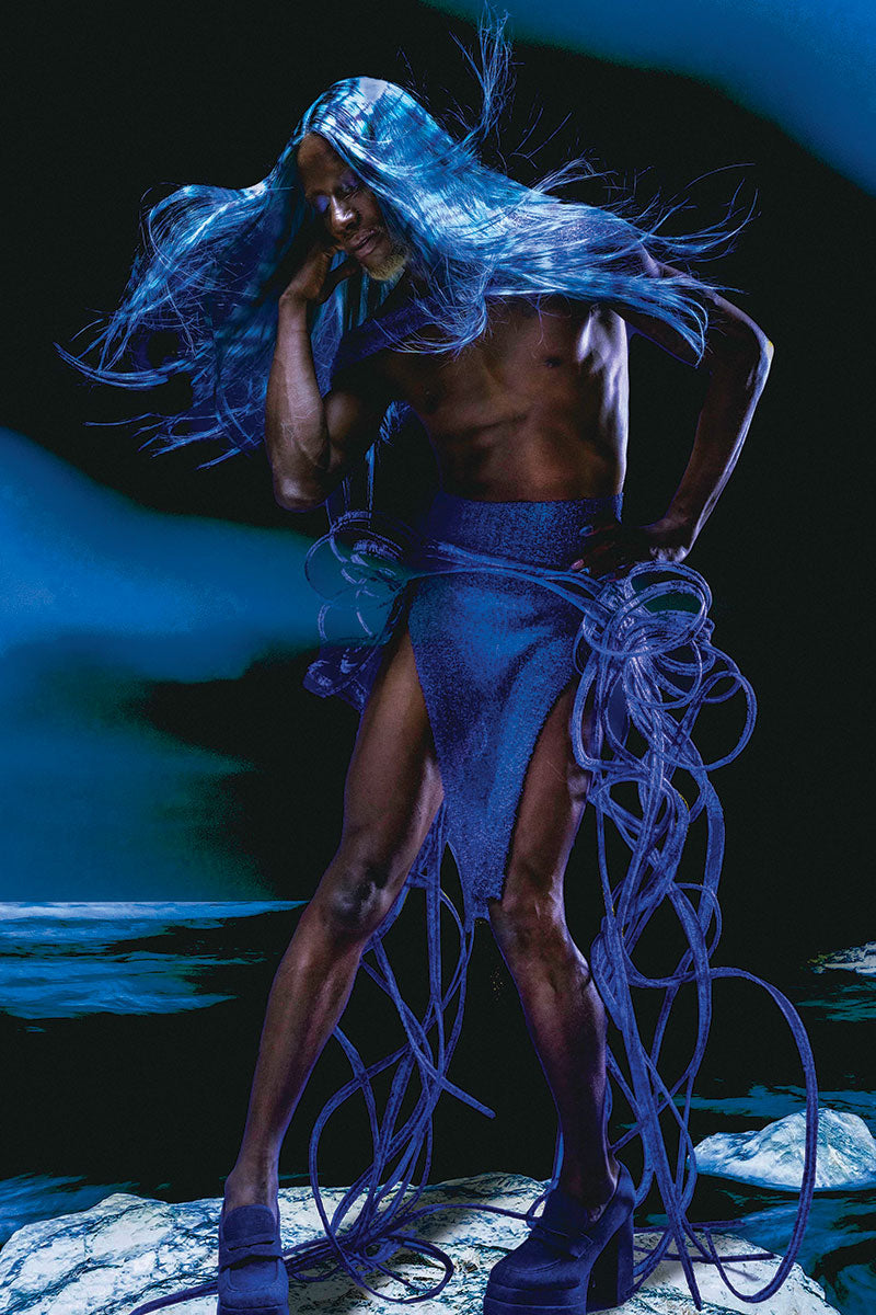 model in surreal blue and black photo shoot. wearing a long patterned blue white and black wig