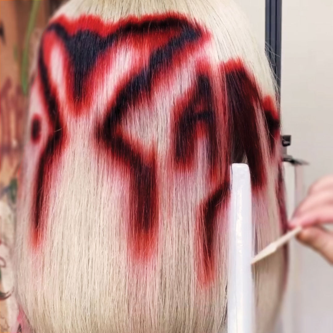a hand combing a white red and black wig on a wig stand