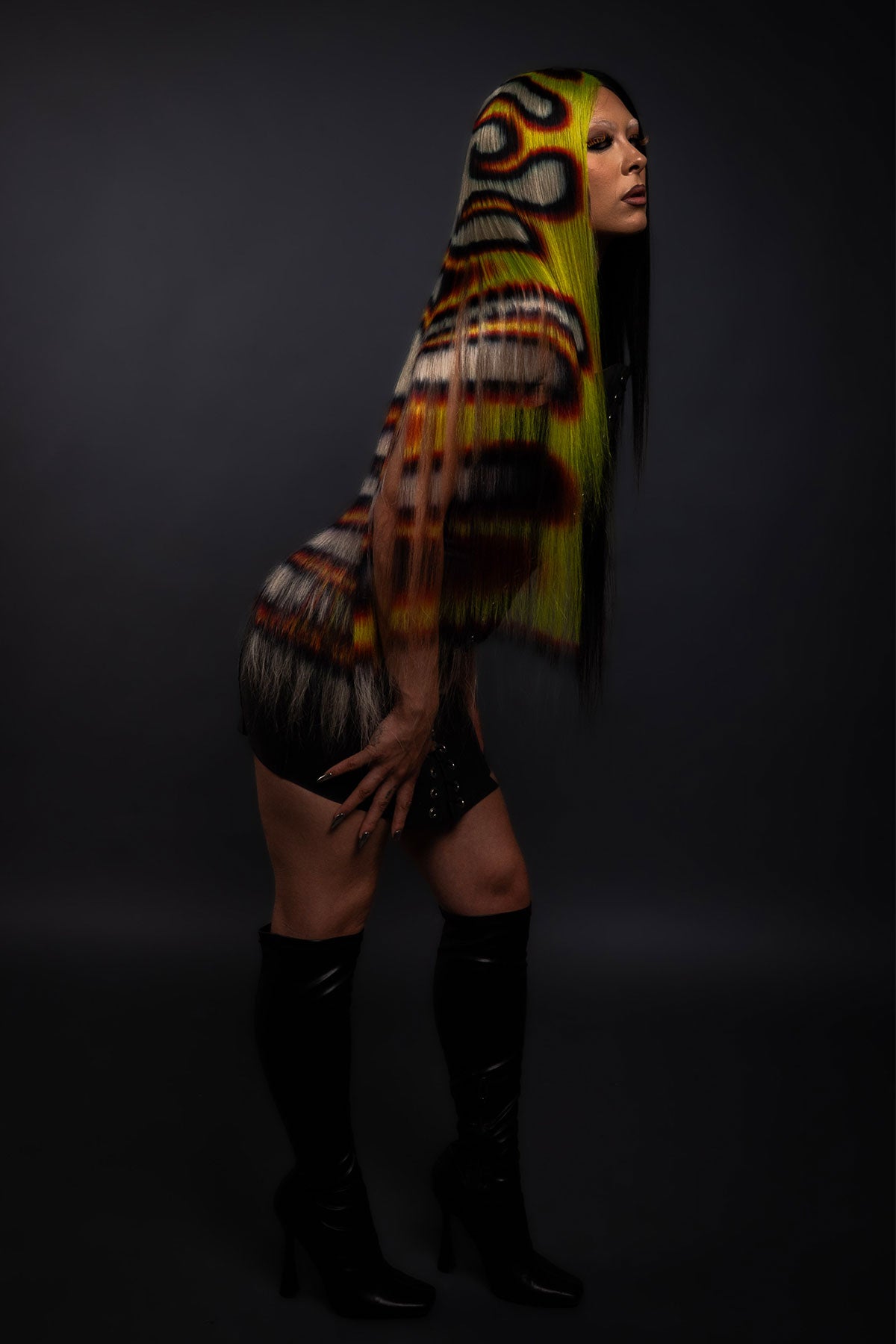 a model in a black dress wearing a black yellow and red fire wig