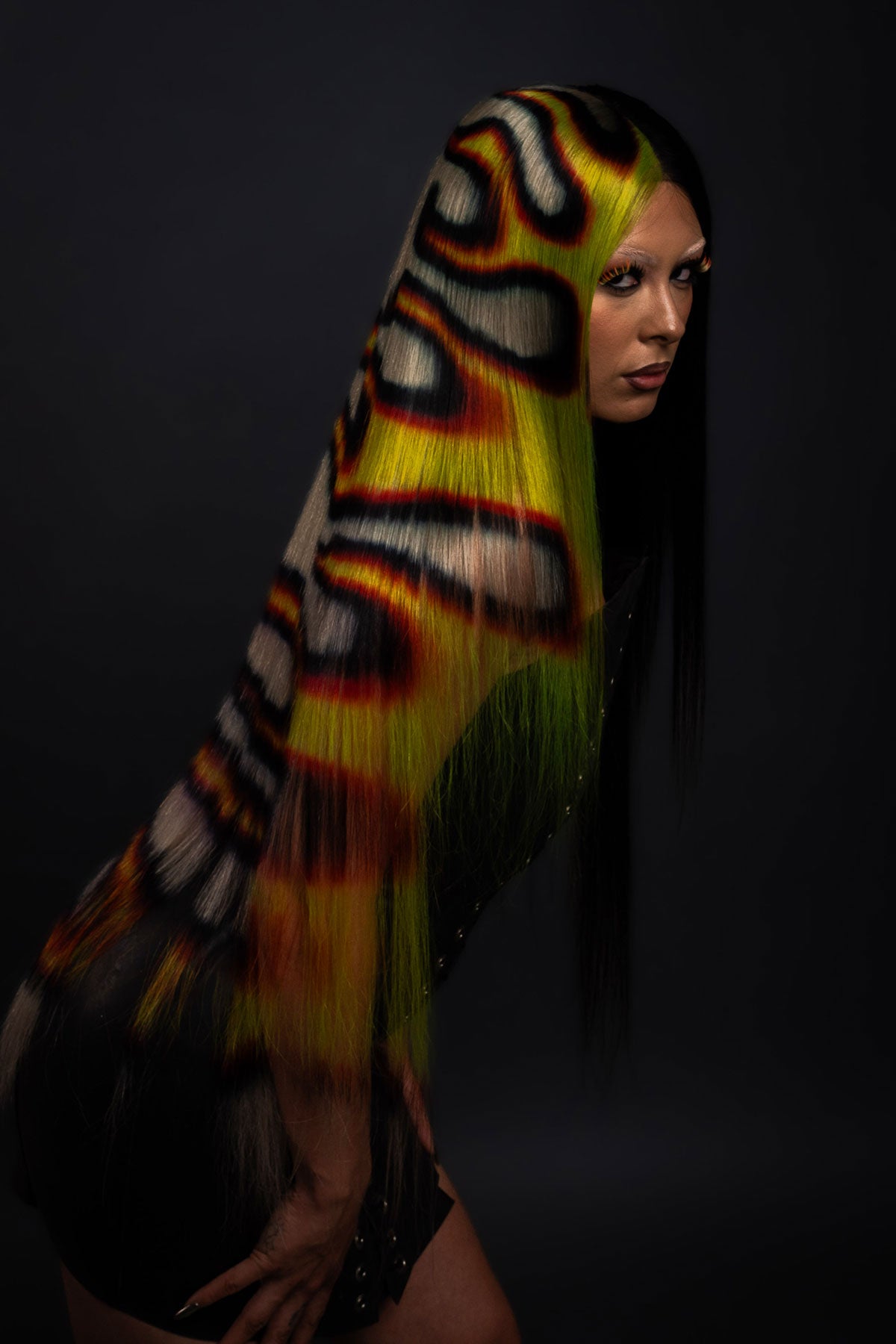 a model in a black dress wearing a black yellow and red fire wig