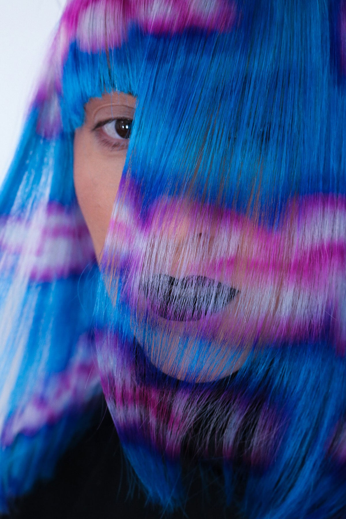 a woman wearing a blue wig with pink and white clouds painted into it