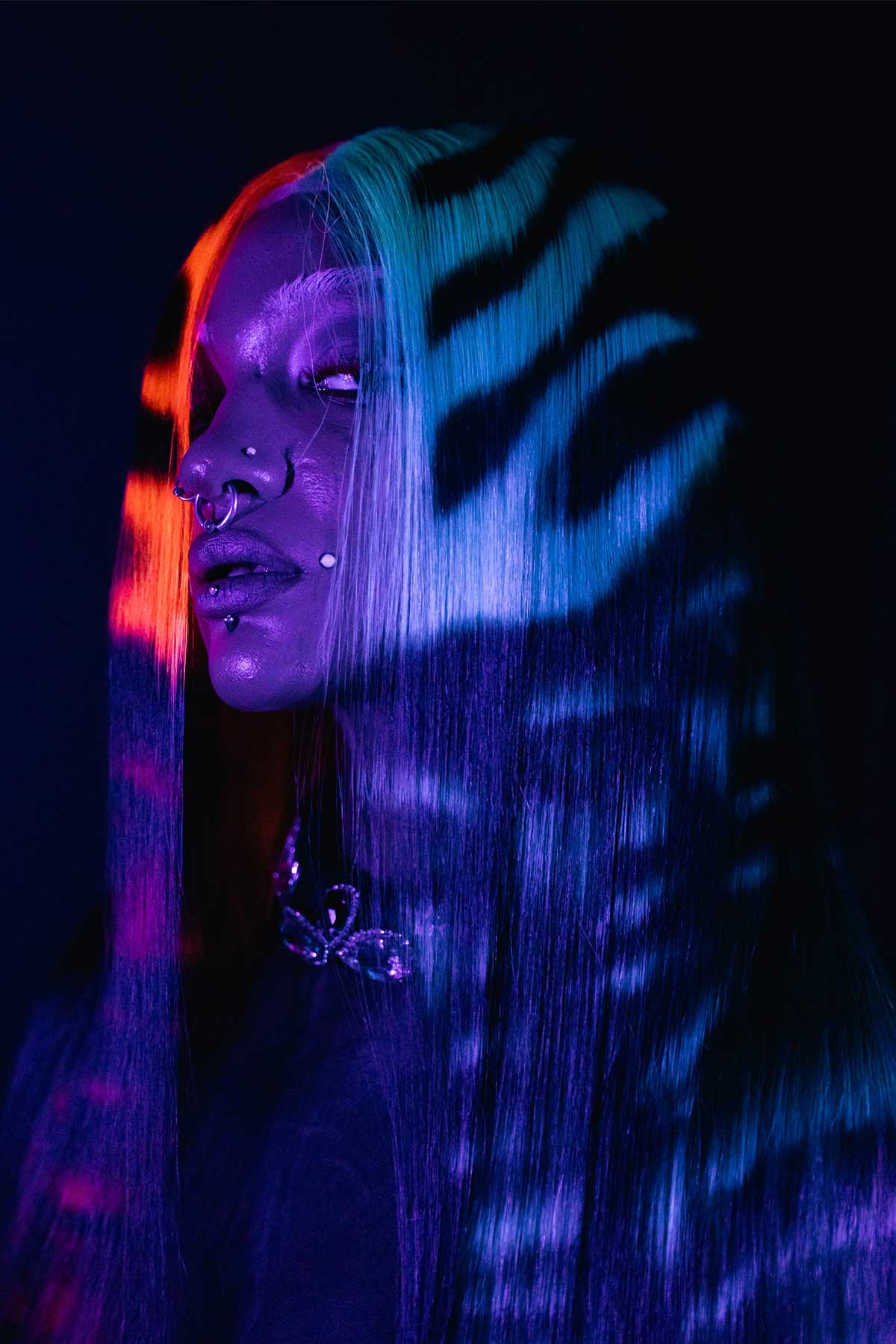 a front side view of a model wearing a black wig with red and blue flames and faces under black light
