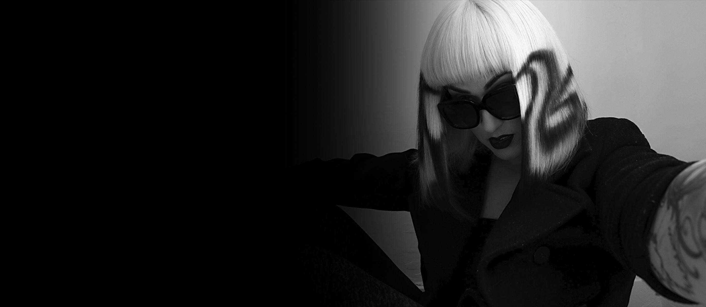 black and white image of shannon in a suit jacket and painted wig