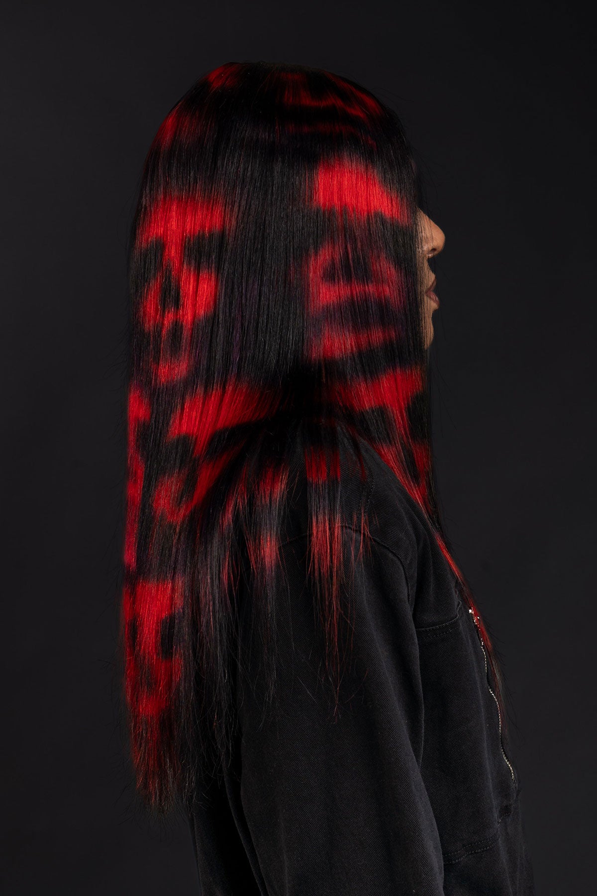 a side view of a model wearing black in a black and red skull wig