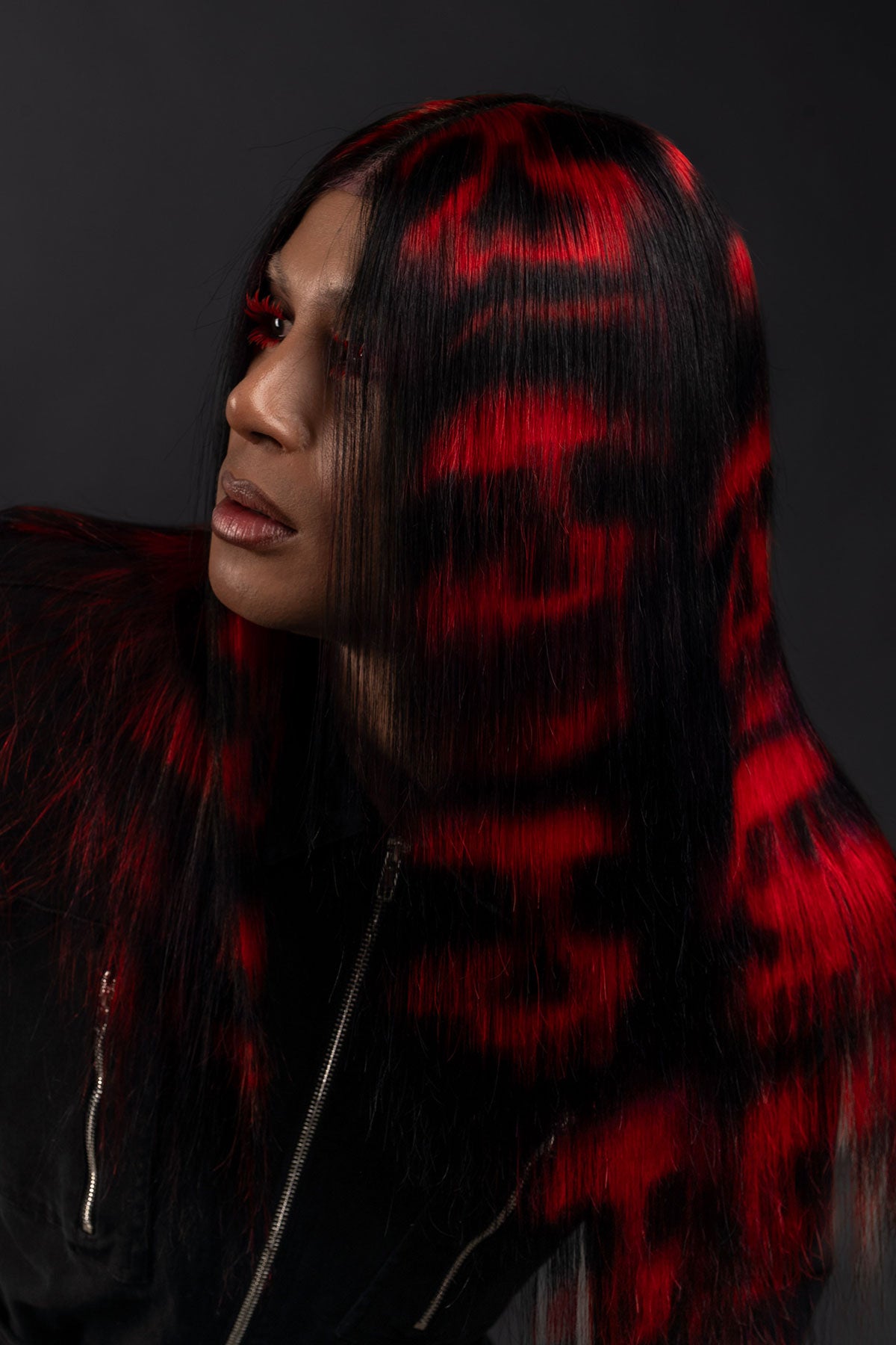 a model wearing black in a black and red skull wig