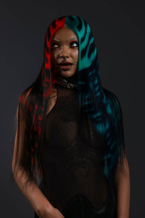 a front view of a model wearing a black outfit and a black waist length wig with blue and red faces painted into it