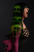 a side view of a model wearing a black and green zombie wig and a fishnet dress 