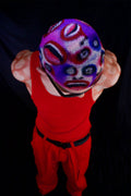 a model in a red outfit wearing a buzzed, colorful wig with faces painted into it